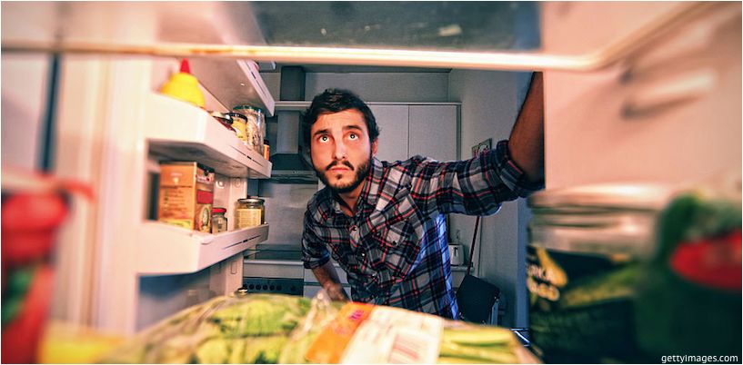 vyras žiūri į šaldytuvą