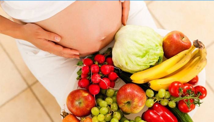 Nėščia moteris su daržovėmis ir vaisiais