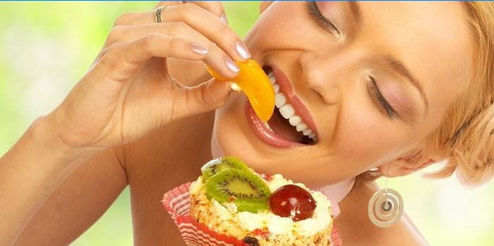 Mergaitė valgo vaisius ir pyragą