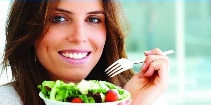 Mergaitė laiko lėkštę su salotomis