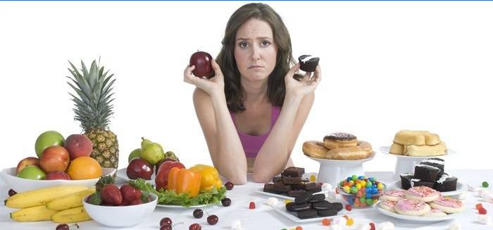 Mergaitė pasirenka tarp saldumynų ir vaisių.