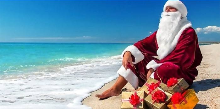 Kalėdų senelis su dovanomis jūros paplūdimyje