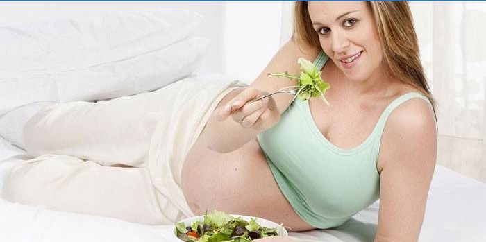 Nėščia mergina valgo salotas