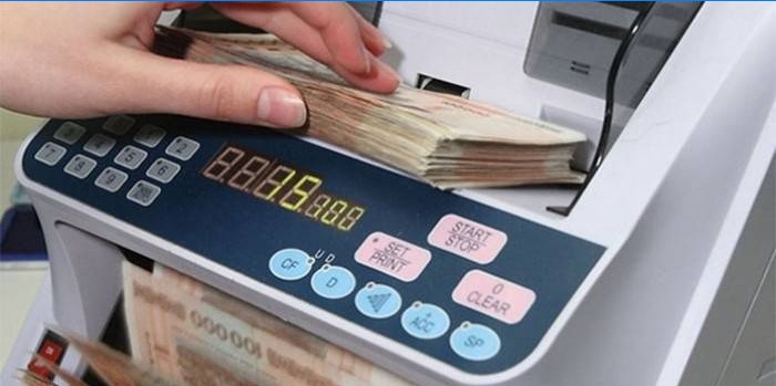 Moteris skaičiuoja pinigus sąskaitos aparatu