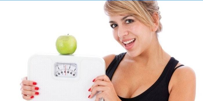Mergaitė su svoriais ir obuoliu