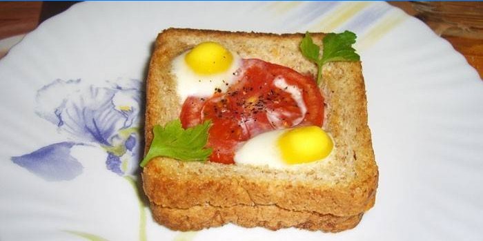Karštas sumuštinis su putpelių kiaušiniais ir pomidoru lėkštėje