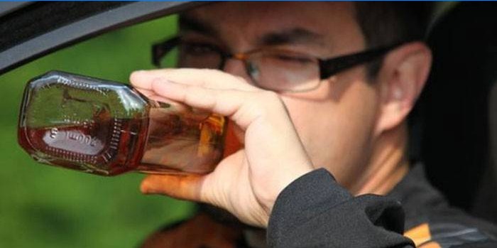 Vyras automobilyje geria alkoholį iš butelio